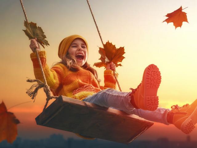 Happy child girl on swing in sunset fall. Little kid playing in the autumn on the nature walk.