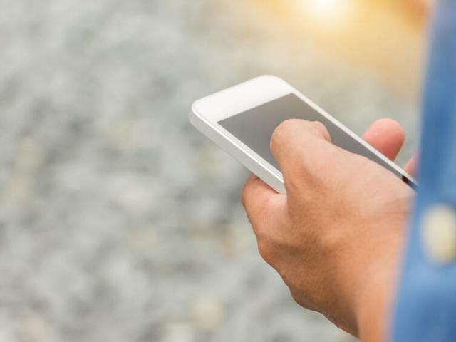 Close up of Engineering Businessman in blue jeans using mobile smartphone blurry background.